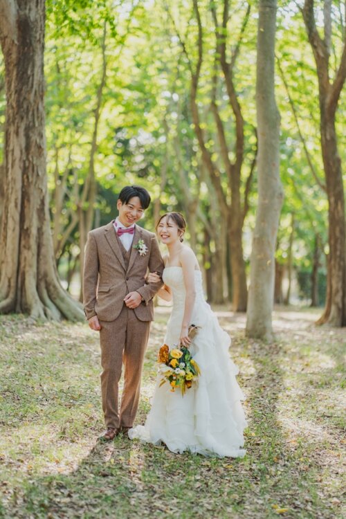 Bride and groom in a tweed suit laughing together in a tree-lined park, a relaxed and natural idea for wedding photography in Japan