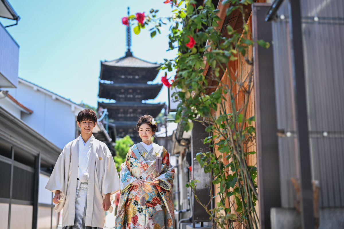 Couple in white hakama and a colorful uchikake on an old Kyoto lane with the Yasaka Pagoda behind, kimono wedding photos of a classic townscape