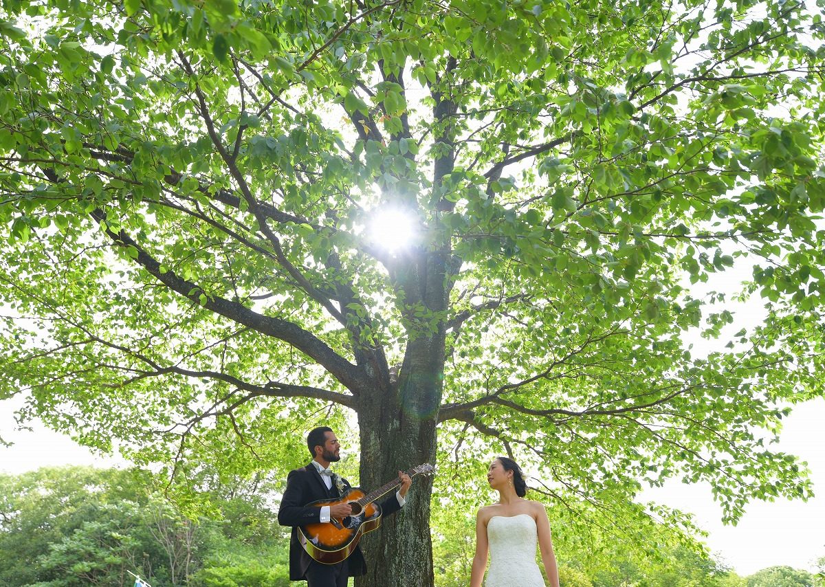 A western-style location photoshoot at the lush Daikou Midorichiku Park, accompanied by the melodic tunes of a guitar.