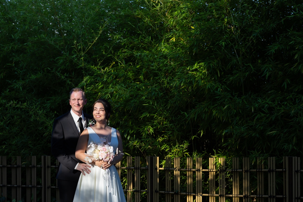 A quiet portrait beside a bamboo fence, dappled sunlight filtering through the greenery, a peaceful moment from their pre-wedding photoshoot in Japan.