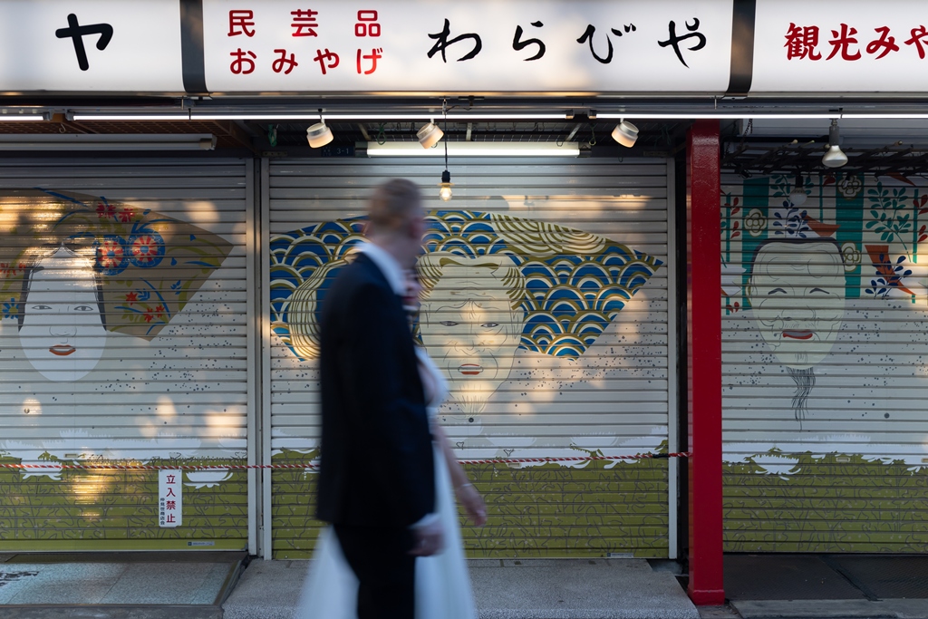 Walking past a shuttered shopfront painted with traditional Japanese motifs, motion blur adding a dreamlike quality.
