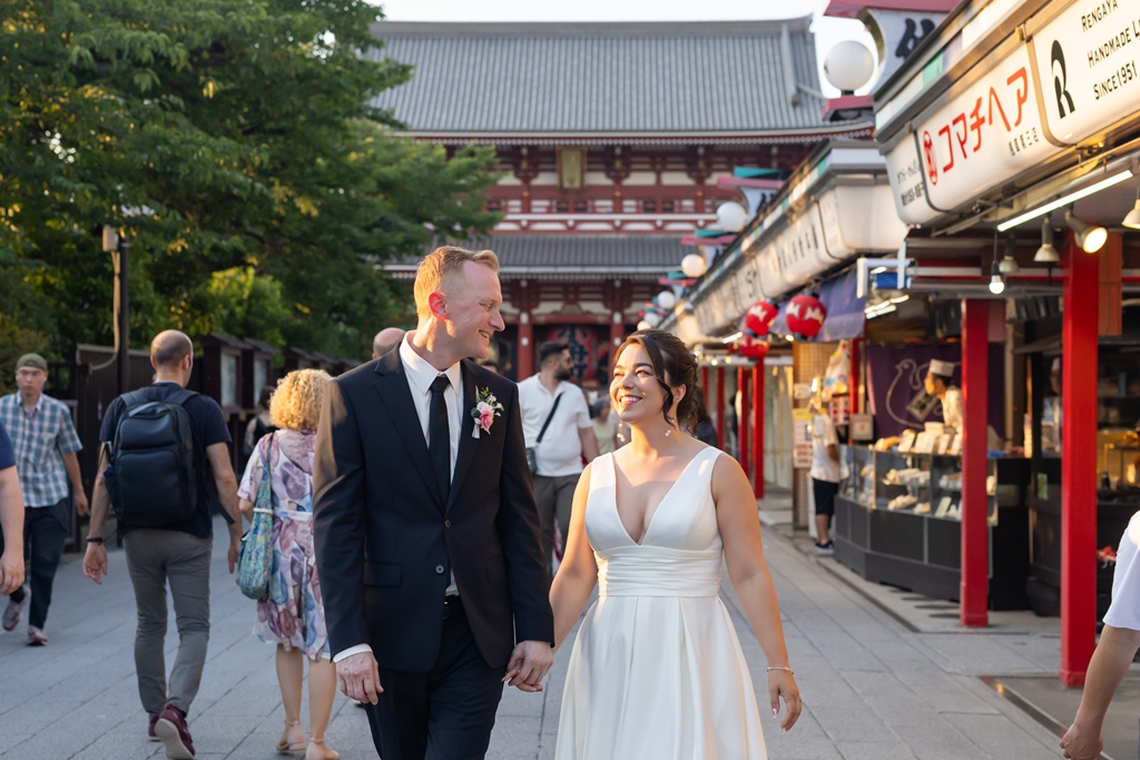 Walking hand in hand down Nakamise shopping street, Asakusa's iconic temple gate glowing warmly in the evening light.