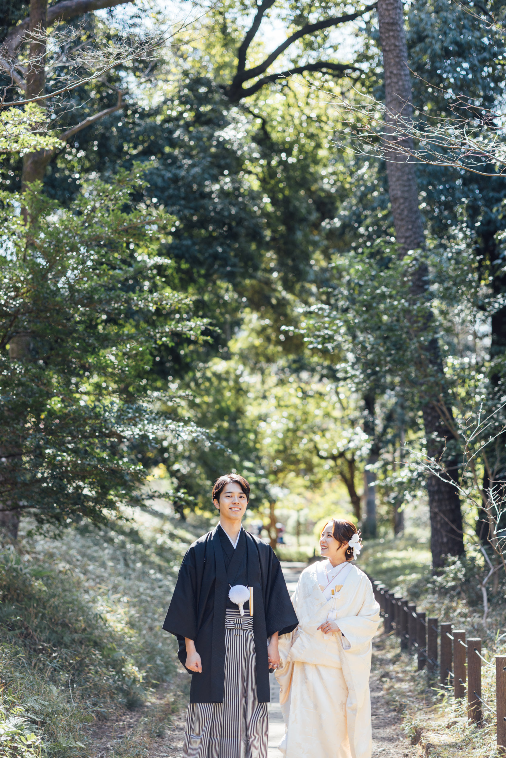 Arisugawa Memorial Park kimono wedding photography — couple in wedding kimono walking the dappled woodland path, natural light filtering through old-growth trees