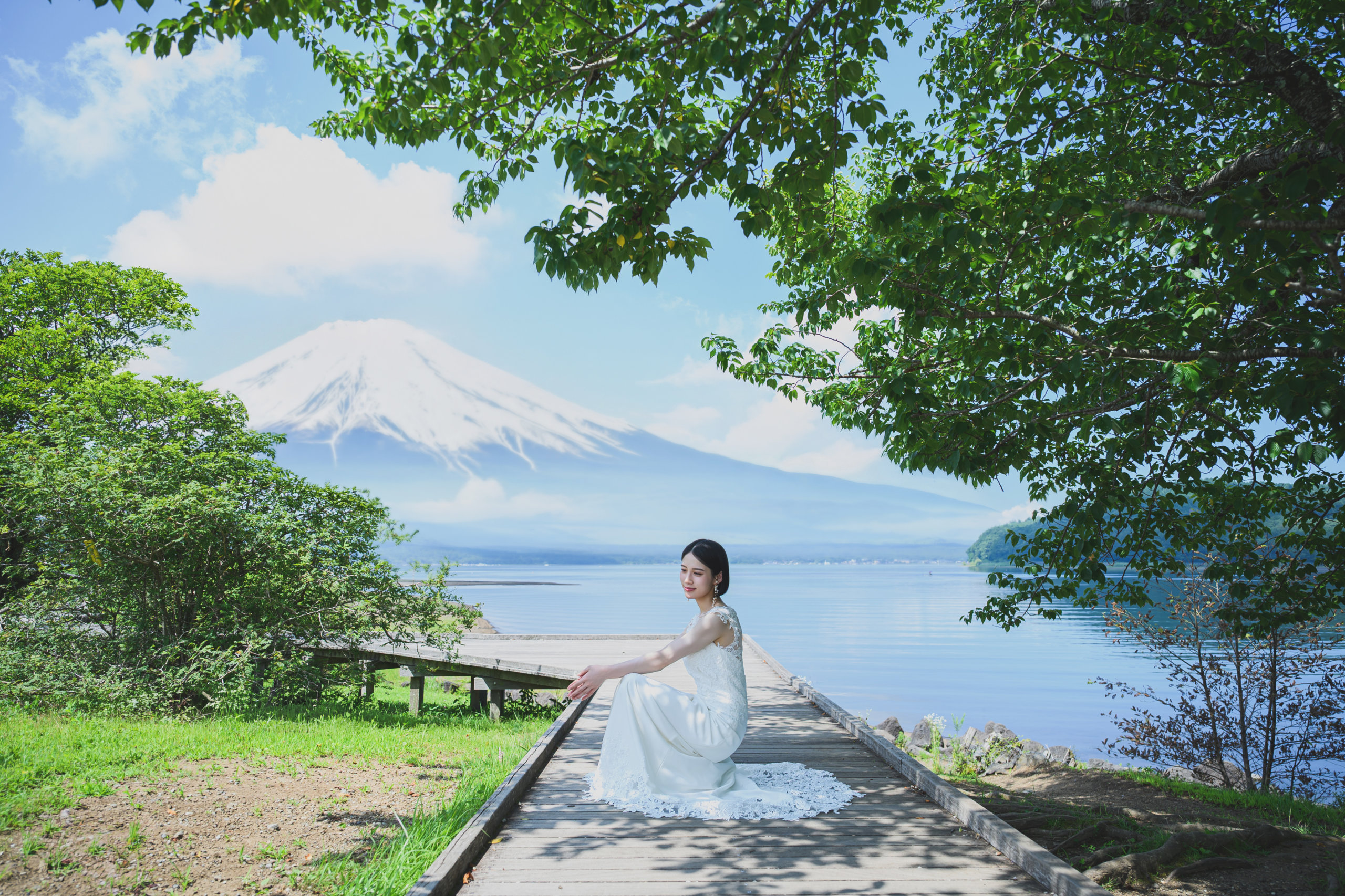 Bride sitting on a lakeside pier with Mt. Fuji in the background at Lake Yamanaka