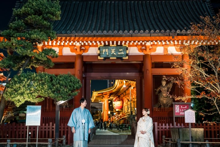 Standing before the illuminated Niten-mon Gate at Senso-ji Temple, its vivid red pillars glowing warmly at night.