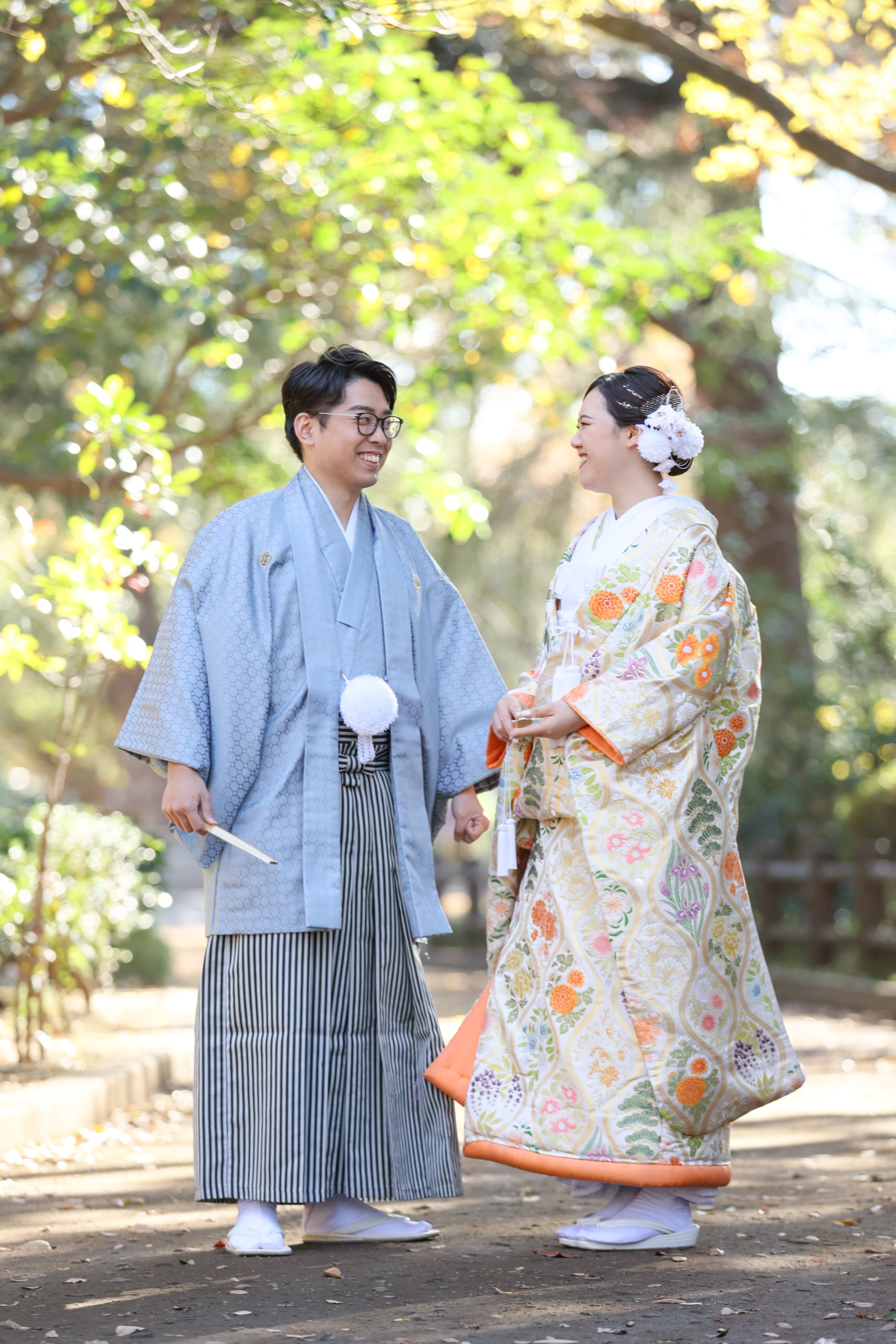 Kimono selection at Arisugawa Memorial Park — white shiromuku against deep green creates pure contrast; vermilion iro-uchikake harmonizes with autumn foliage
