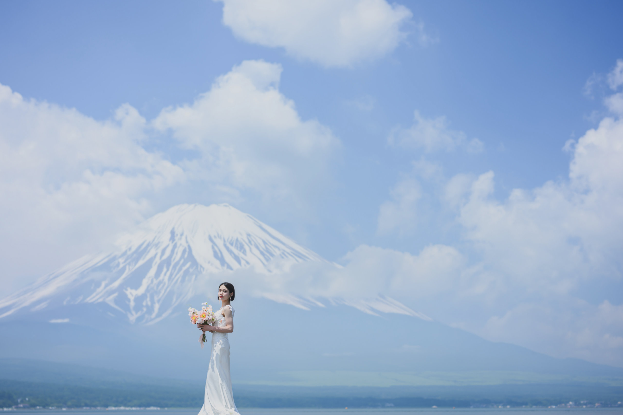 Bride holding a bouquet with Lake Yamanaka and Mt. Fuji in the background