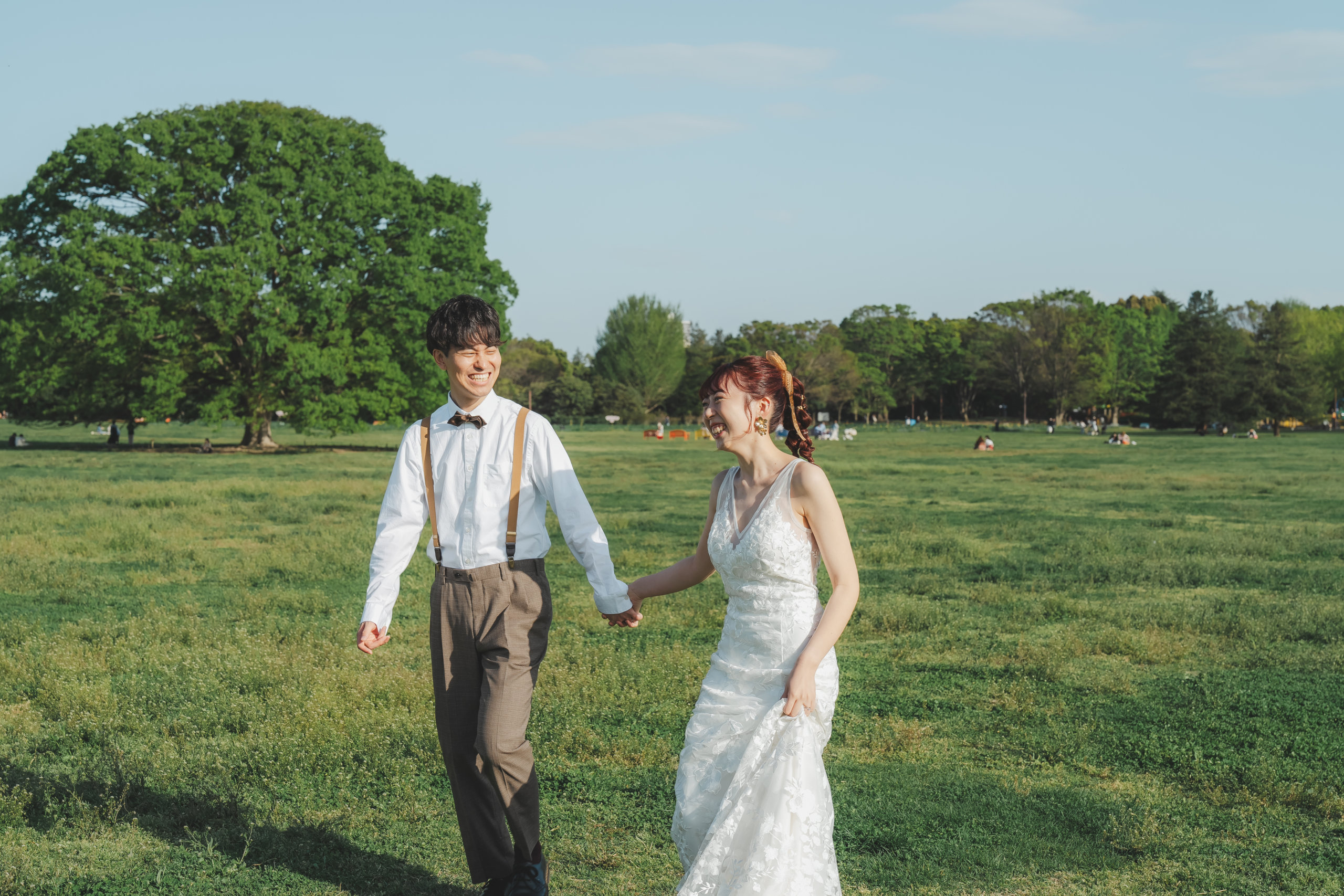Showa Memorial Park meadow wedding photography — bride's long veil caught by the wind across the vast open lawn, a dramatic shot unique to this location