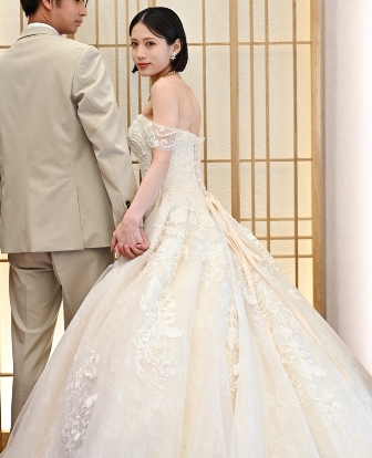 A-Line style wedding dress (AE03): A voluminous A-line gown adorned with luxurious three-dimensional floral lace. The soft ivory hue and layers of delicate tulle create an elegant and glamorous look, while the beautifully detailed back adds a striking presence from every angle.