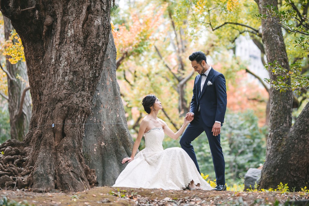 Hibiya Park autumn foliage wedding photography — red, orange and gold leaves against white wedding dress, with the urban context of central Tokyo visible in the background