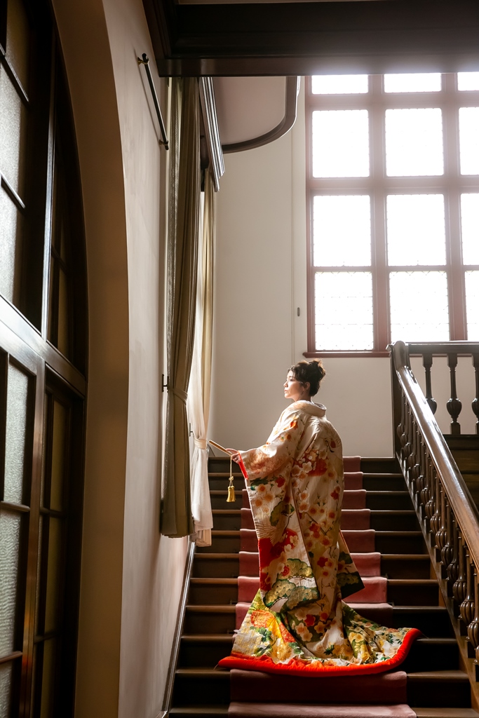 Former Furukawa Residence grand staircase wedding photography — the red-carpeted staircase and stained glass windows create a period atmosphere impossible to replicate elsewhere in Tokyo