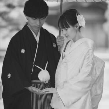Black and white portrait of a couple in shiromuku and montsuki sharing a wagasa parasol, a timeless kimono wedding photo in Japan
