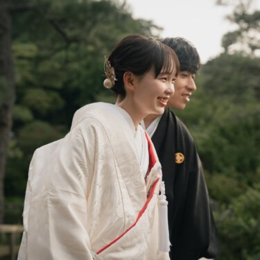 Laughing bride in shiromuku with her groom on a garden bridge surrounded by pine trees captured in this kimono wedding photos in Japan