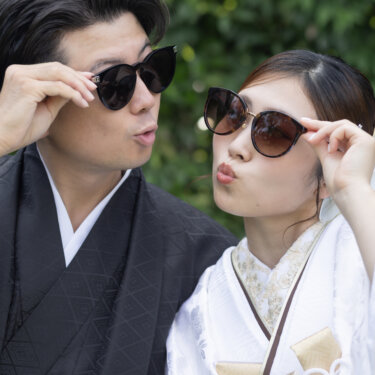 Bride and groom in traditional kimono posing with sunglasses and pursed lips, a stylish and playful pre-wedding portrait