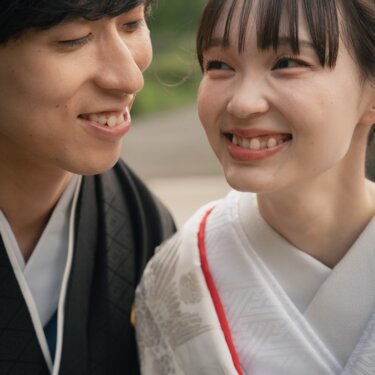 Bride in a white kimono and groom in montsuki smiling at each other up close, a joyful moment of Japan wedding photography
