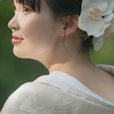 Profile of a bride in a white shiromuku with an orchid and mizuhiki hair ornament, glowing in soft afternoon light at Sankeien Garden