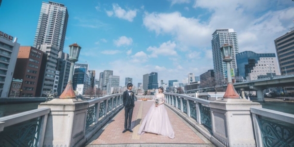 Standing on a historic iron bridge over the river at Nakanoshima Park, Osaka's skyline rising on either side.