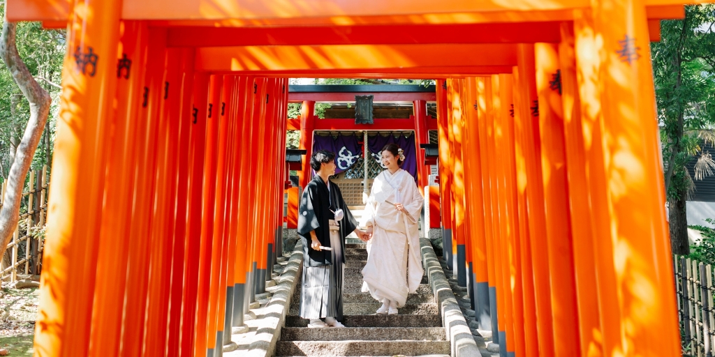 Walking hand in hand through a tunnel of vivid vermillion torii gates at Yokiso, a striking backdrop for this Nagoya wedding photography session.
