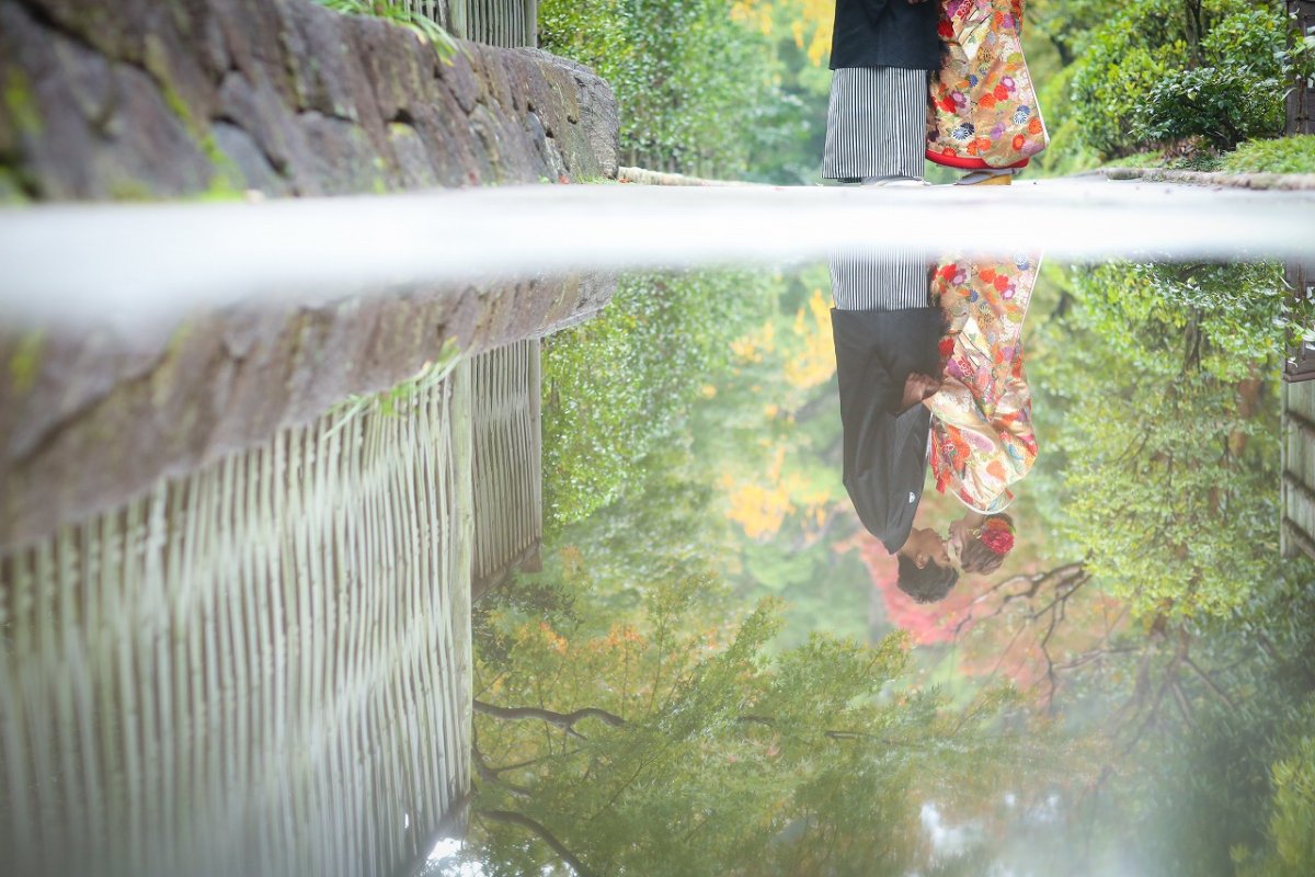 A couple in wedding attire reflected in glass with a city backdrop
