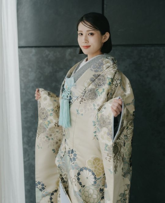 Souka Yuuga style wedding dress (DMOS17): A refined iro-uchikake with a soft pink-beige lining that appears with each movement. Fresh green and silver-gray florals on a white base create a graceful balance of purity and mature elegance.