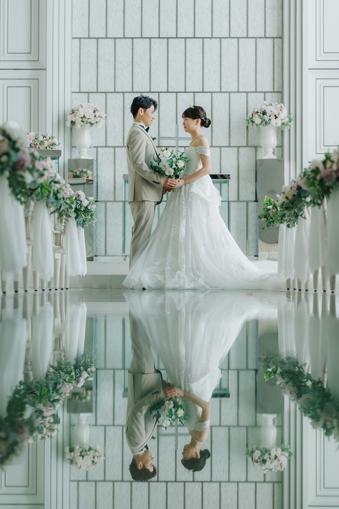 A bride in a gown with a long train standing by the water