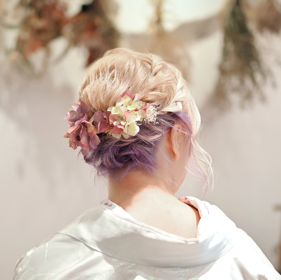 A pastel-dyed bridal updo accented with dusty rose and cream dried hydrangea, paired with a white kimono.