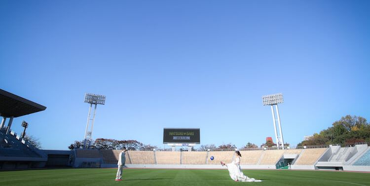 Playing catch on the empty pitch of a Nagoya soccer stadium, the scoreboard glowing softly in the afternoon light.