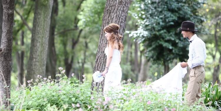 Wandering hand in hand through a wildflower meadow at Meijo Park, a wide-brimmed hat and bouquet completing the look.