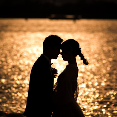 Silhouette of the couple touching foreheads against golden sunlight sparkling on Tokyo Bay, sunset wedding photography in Odaiba