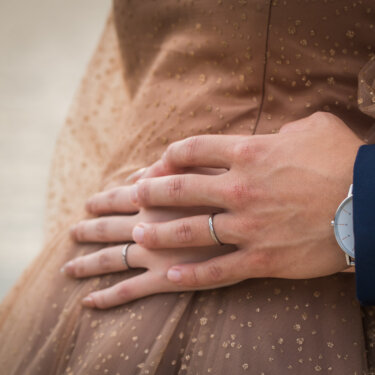Close-up of the groom's hand with his wedding ring resting on the bride's sparkly tulle gown, a detail from a Tokyo wedding photoshoot
