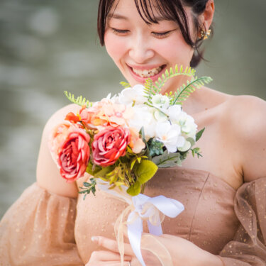 Close-up of a laughing bride with a braided updo cradling her rose bouquet, a natural moment from a Japan wedding photography session