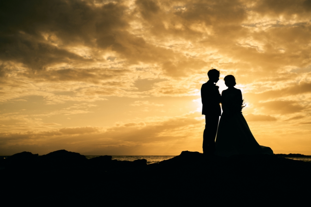 Silhouette of a bride and groom against an orange sunset sky on Jogashima