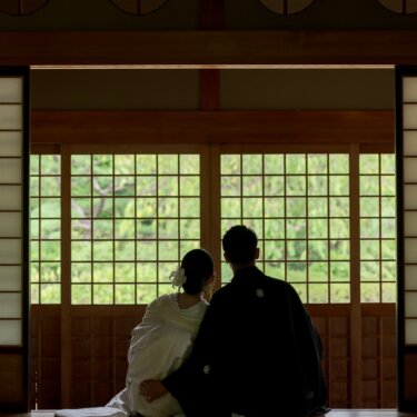 Back view of the couple in kimono sitting on tatami before bright shoji windows beneath round lattice windows in a traditional room at Daisen Park Japanese Garden, a serene wedding photography composition