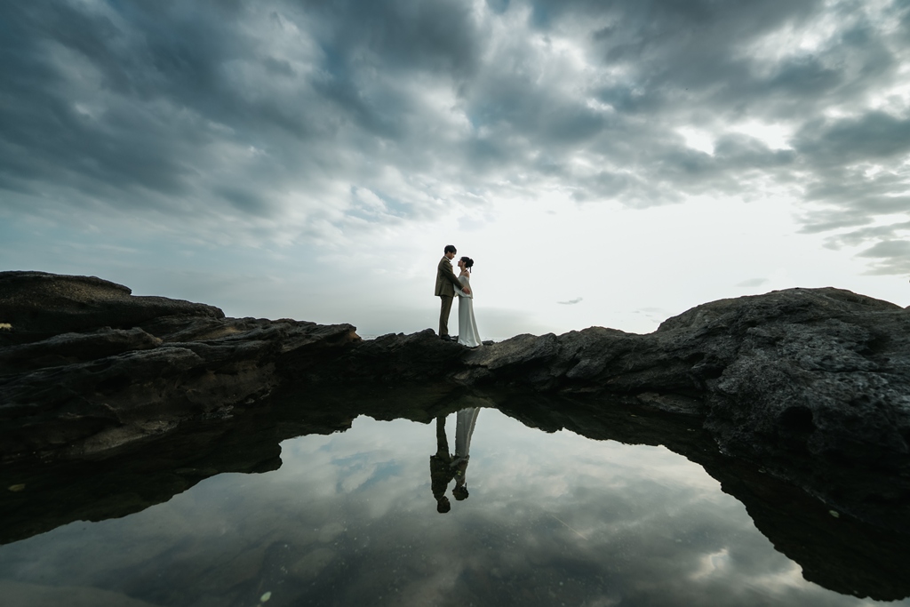 Silhouette of a wedding couple reflected in a tide pool on the rocky coast of Jogashima, creative wedding photos in Japan