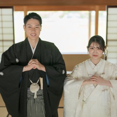 Groom in montsuki and bride in shiromuku standing with hands folded in a tatami room lined with shoji screens, a classic symmetrical composition for Japan wedding photography