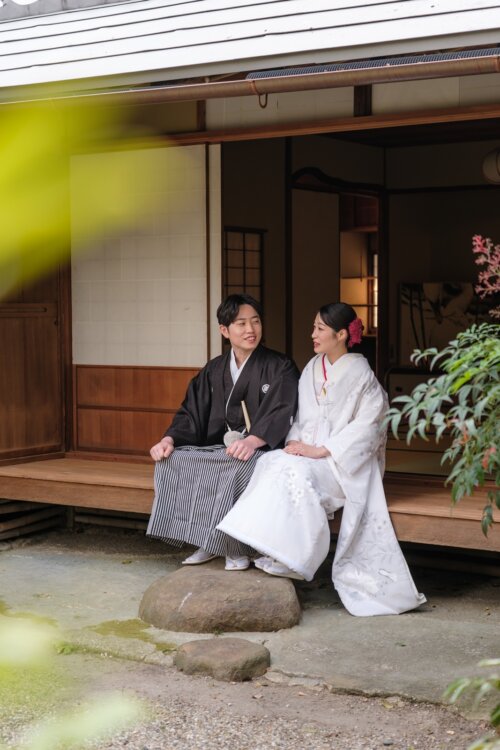 Groom in black montsuki hakama and bride in shiromuku sitting on the veranda of a teahouse in a Japanese garden, a pre-wedding photoshoot in Japan