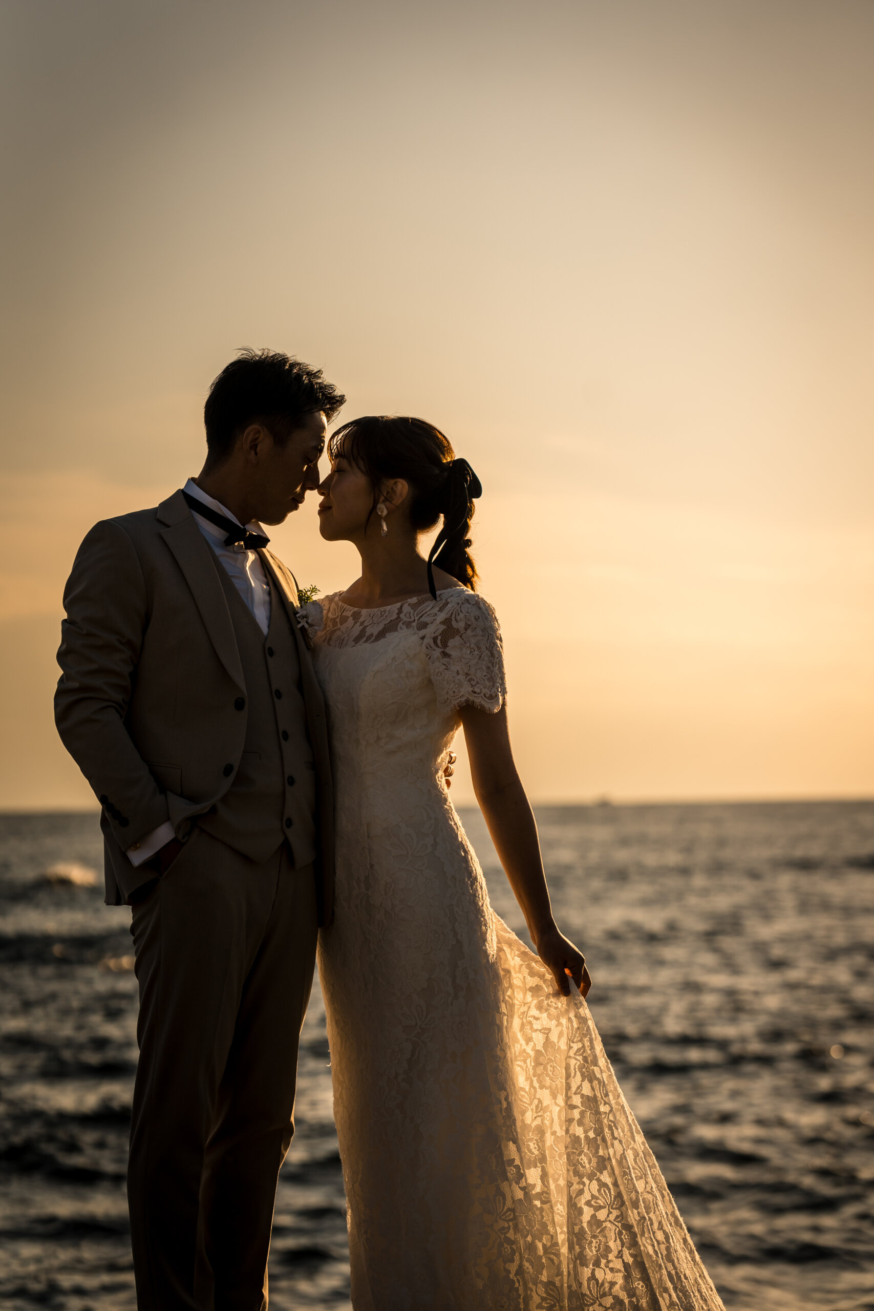 Wedding couple embracing against the setting sun over the sea at Jogashima, sunset wedding photography in Japan
