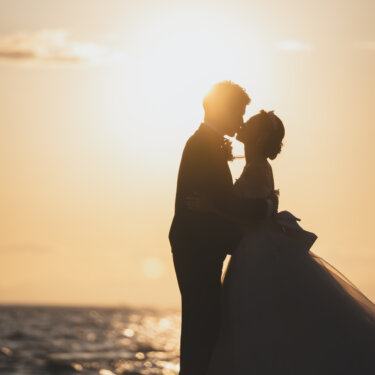 Silhouette of the bride and groom sharing a kiss against the golden sunset over the sea, a romantic moment from a beach pre-wedding photoshoot in Japan