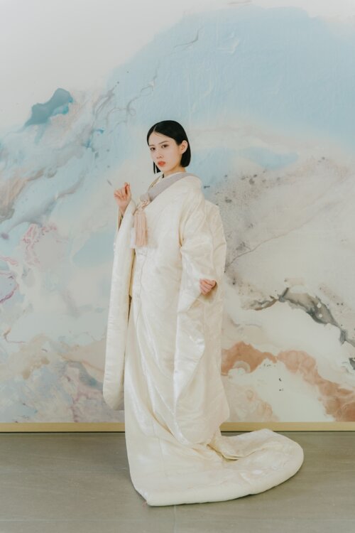 Full-length shot of a bride in a shiromuku with a long trailing hem before a watercolor-style art wall, Japan wedding photography in our studio (Shiromuku AS104).