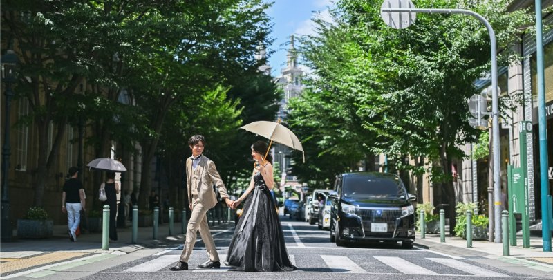A couple in cream suits sits at a small table, representing the Wedding Avenue official English site.