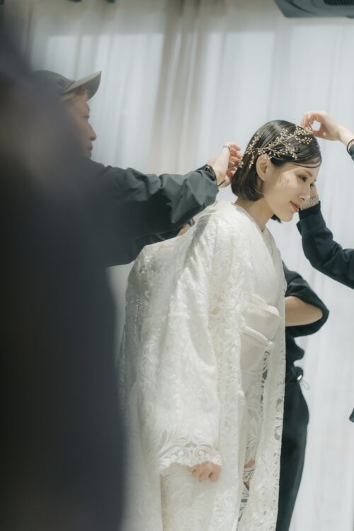 Behind-the-scenes moment as our stylist adjusts the gold headpiece of a bride in a shiromuku before her pre-wedding photoshoot in Japan (DE101).