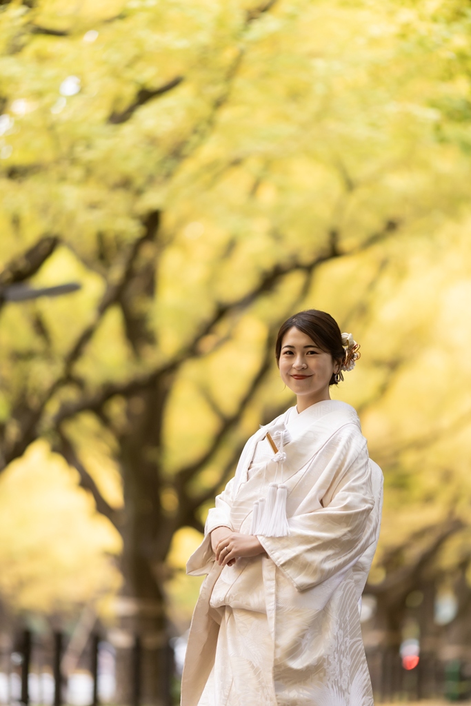 Bride in white shiromuku with a modern updo and flower hair ornaments standing among golden ginkgo trees in Tokyo