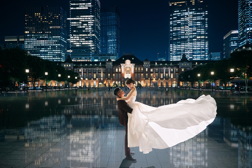 The groom lifts the bride in front of the illuminated Tokyo Station Marunouchi building, a pre-wedding photoshoot with a wedding movie in Japan