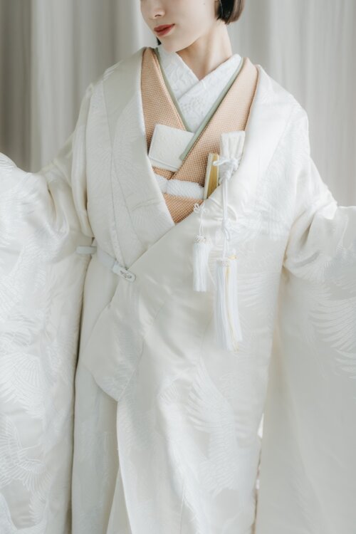 Close-up of the DS101 shiromuku with a hakoseko purse, tassel ornament and beige collar, a detail shot from kimono wedding photos in Japan