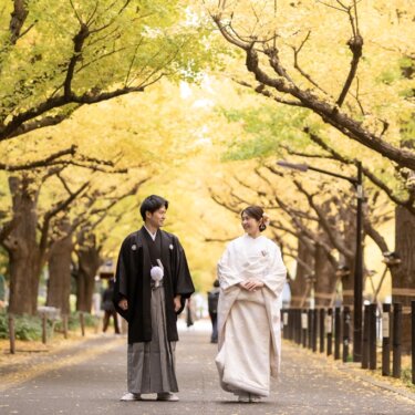 Bride in white shiromuku and groom in montsuki hakama walking under the golden ginkgo trees of Jingu Gaien, autumn kimono wedding photos in Tokyo