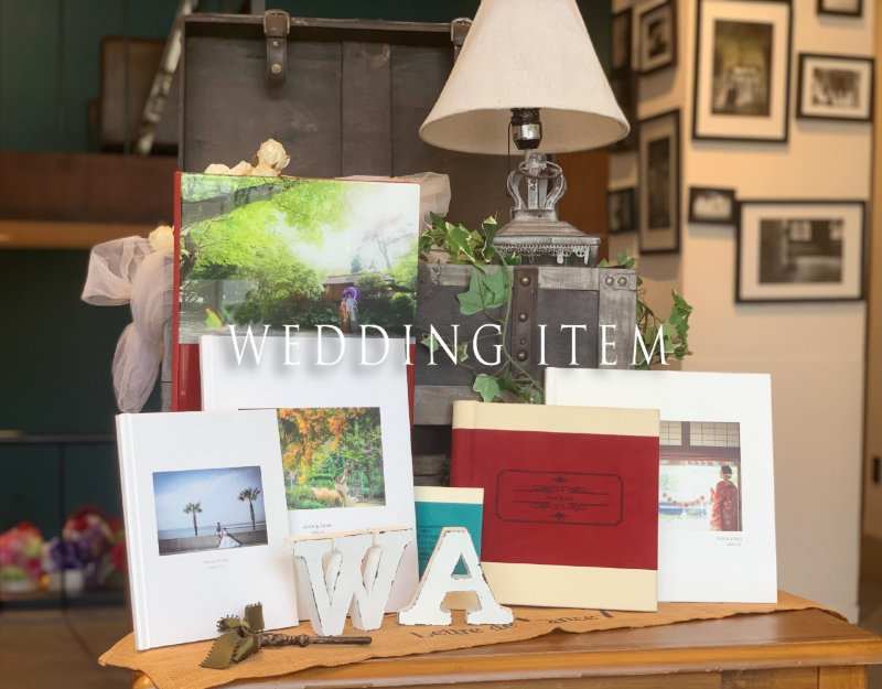 'Wedding Item' banner featuring custom photo albums displayed on a vintage table with dried flowers.