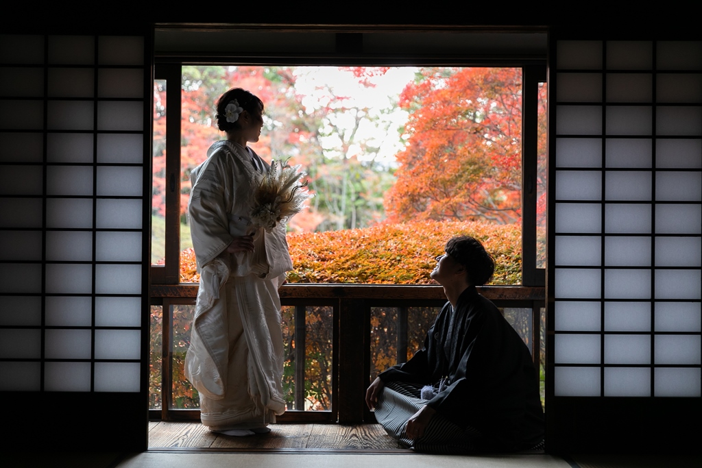 Bride in shiromuku holding a dried flower bouquet and groom in montsuki sitting on a veranda overlooking autumn maple leaves, a kimono pre-wedding photoshoot in Nagoya